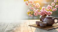 Traditional tea ceremony setup with cherry blossom branches on rustic wooden table. Peaceful zen atmosphere for meditation and relaxation concepts.