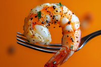 Macro shot of seasoned cooked shrimp on fork against vibrant orange background, garnished with black pepper and fresh herbs, showcasing culinary detail.