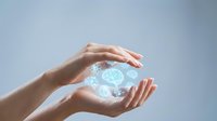 Young woman with light skin tone holding glowing digital brain hologram between hands against blue background. Concept for artificial intelligence, technology innovation, and neural network development.