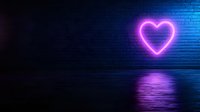 Glowing neon heart shape on dark brick wall with reflection on wet surface, purple and blue colors create romantic urban night atmosphere.