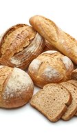 Assorted artisan breads including crusty baguettes, round loaves, and sliced whole wheat bread isolated on white background for bakery, food, and culinary design use.