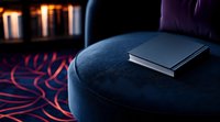 Closed book on dark blue velvet ottoman against dramatic lighting and red patterned carpet, creating mysterious moody atmosphere for literature and reading concepts.