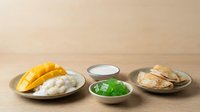 Mango sticky rice with fresh mango slices, glutinous rice, coconut milk sauce, and crispy fried shallots on ceramic plates for Asian cuisine food photography.