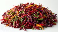 Vibrant pile of dried red chili peppers garnished with fresh herbs on white background, showcasing spicy ingredients for cooking and seasoning.