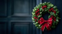 Festive Christmas wreath with green leaves and red berries adorned with elegant bow hanging on dark door, creating holiday atmosphere.