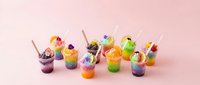 Colorful layered beverages with fresh fruit, edible flowers, and straws arranged on pink background for beverage, food styling, and hospitality design projects.