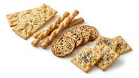 Assorted crispy crackers and breadsticks with sesame seeds and grains arranged on white background for food and bakery product advertising.