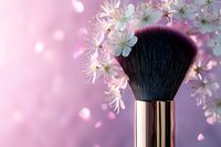 Luxury makeup brush with white cherry blossoms on pink background. Soft focus professional cosmetic applicator with spring flowers creates romantic beauty scene.