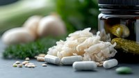 Fresh fermented foods and probiotic supplements arranged on gray surface with pickled cucumbers, sauerkraut, pills and raw eggs in soft natural light.