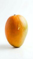 Fresh mango with golden-orange skin isolated on white background, suitable for food packaging, recipe blogs, and culinary design projects.