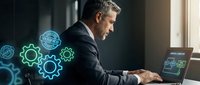 Middle-aged man in business suit working at laptop with glowing gear and technology icons floating around him, representing digital transformation and industrial automation.