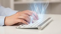 Professional hands typing on white keyboard with glowing digital data streams and light effects emerging from screen in modern office workspace.