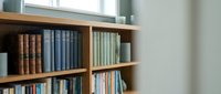 Wooden bookshelf with colorful books in modern home library interior. Educational literature collection for reading and studying in bright room.