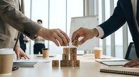 Two business professionals collaborating to build wooden blocks spelling SEO in modern office environment for digital marketing strategy development.