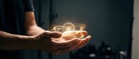 Hands cupping glowing light bulb with warm illumination representing innovation, creativity, and bright ideas for business and technology concepts.