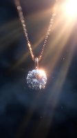 Sparkling diamond pendant on rose gold chain catching sunlight rays against dark background, creating magical glow and reflections. Luxury jewelry concept.