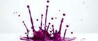 Purple liquid splash with dynamic droplets and crown formation against white background for creative design projects and artistic compositions.