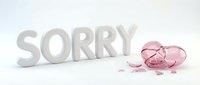 Word SORRY in white letters next to a shattered pink glass heart on a white background, symbolizing apology, regret, and emotional pain.