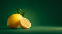 Fresh yellow lemon with green leaves and sliced half on emerald background for healthy nutrition and citrus fruit cooking concepts.
