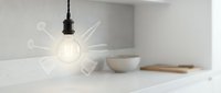 Modern minimalist kitchen interior with glowing pendant light bulb and white ceramic bowls on marble countertop for contemporary home design concepts.