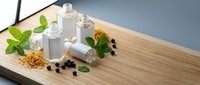 Natural skincare bottles with herbs and botanicals on wooden surface for organic beauty product packaging and wellness branding concepts.