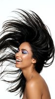 Young woman with long black hair in motion, colorful eyeshadow, and glowing skin against white background. Hair care and beauty cosmetics concept.