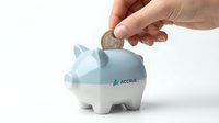 Hand inserting coin into blue and white piggy bank for savings and financial planning on white background.