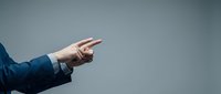 Professional businessman hand pointing finger gesture on neutral gray background for business presentation and corporate communication concepts.