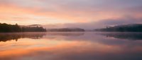 Serene lake at sunrise with pink and orange sky reflecting on calm water, misty forest shoreline, peaceful dawn landscape for nature and travel projects.