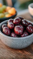 Fresh ripe plums with water drops in gray ceramic bowl on wooden table. Closeup of juicy purple fruits with natural lighting for food photography.