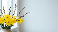 Fresh yellow daffodils and pussy willow branches in glass vase create elegant spring arrangement on white windowsill with natural light and copy space.