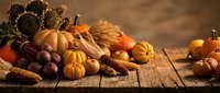 Autumn harvest display with pumpkins, corn, sunflowers and seasonal produce arranged on rustic wooden table for fall decorating and thanksgiving celebrations.