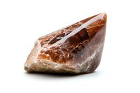 Natural brown smoky quartz crystal point with raw edges and translucent surface showing internal fractures on white background, isolated mineral specimen.
