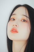Young Asian woman with coral lipstick and natural makeup looking up against white background, showcasing fresh dewy skin and long black hair in beauty portrait.