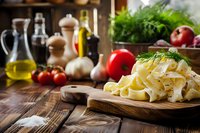 Fresh pasta with herbs on wooden cutting board surrounded by cooking ingredients including olive oil, tomatoes, and spices in rustic kitchen setting.
