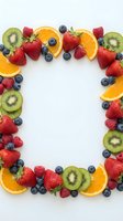 Fresh mixed fruit frame with strawberries, blueberries, raspberries, kiwi and orange slices arranged on white background with copy space for text.