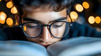 Young person wearing glasses reading book in evening with warm bokeh lights background, creating cozy atmospheric mood for education and literature concept.