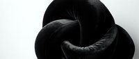 Abstract black twisted form with flowing curves and organic shapes creating dramatic shadows on white background for modern design projects.