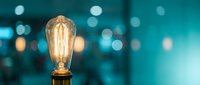 Vintage Edison bulb glowing warmly against blurred city lights background. Retro lighting concept for creative projects and modern interior design.