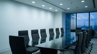 Modern conference room with long glass table and black ergonomic chairs, featuring floor-to-ceiling windows overlooking city skyline, ideal for corporate meetings and business presentations.