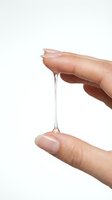 Hand holding clear gel or serum droplet stretching between fingers, demonstrating product texture and viscosity for skincare, cosmetics, and beauty applications.
