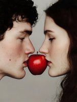 Young couple biting red apple together in romantic conceptual portrait against neutral background, symbolizing temptation and forbidden love.