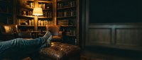 Cozy home library with warm lighting, leather armchair and wooden bookshelves creating intimate reading atmosphere for relaxation and study.