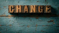 Vintage wooden letterpress blocks spelling CHANGE on a rustic teal painted wood background, evoking transformation and motivation concepts.
