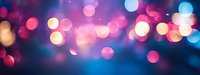 Vibrant bokeh lights creating dreamy atmosphere with pink and blue blurred circles against dark background, abstract defocused panoramic composition.