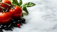 Fresh ripe tomatoes on vine with water drops, blueberries and basil leaves arranged on white marble background with copy space for food photography.