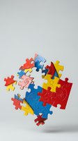 Colorful jigsaw puzzle pieces floating in mid-air against white background, teamwork and problem solving concept for business presentations and educational materials.