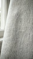 Light gray woven fabric draping near a window, showcasing textile weave pattern and natural light for interior design and home decor projects.