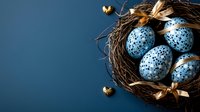 Speckled blue Easter eggs in natural twig nest with golden ribbon and small decorative hearts against dark blue background. Seasonal spring celebration.