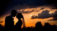 Romantic wedding couple silhouette against dramatic sunset sky with golden clouds, bride and groom intimate moment for marriage celebration designs.